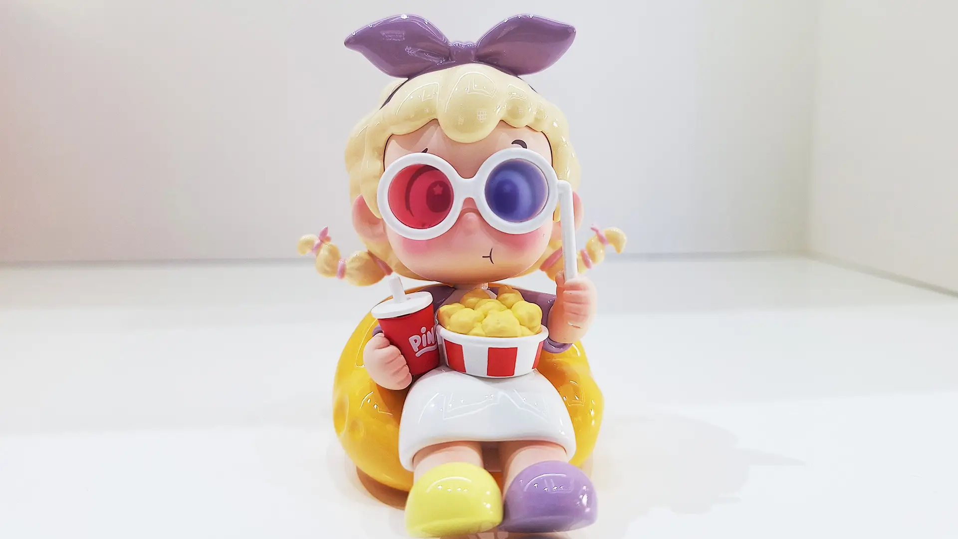 vinyl figure PINY,the toy is sitting on a banana-shaped seat to watch 3d movies