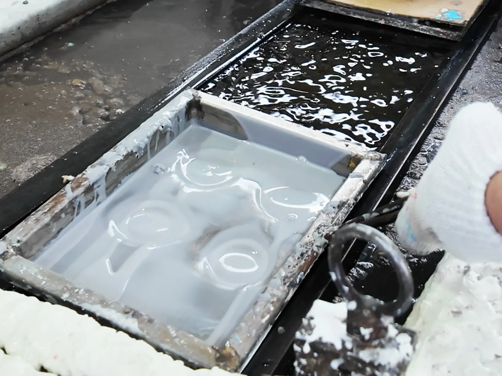 The vinyl mold is being heated in a hot oil tank.