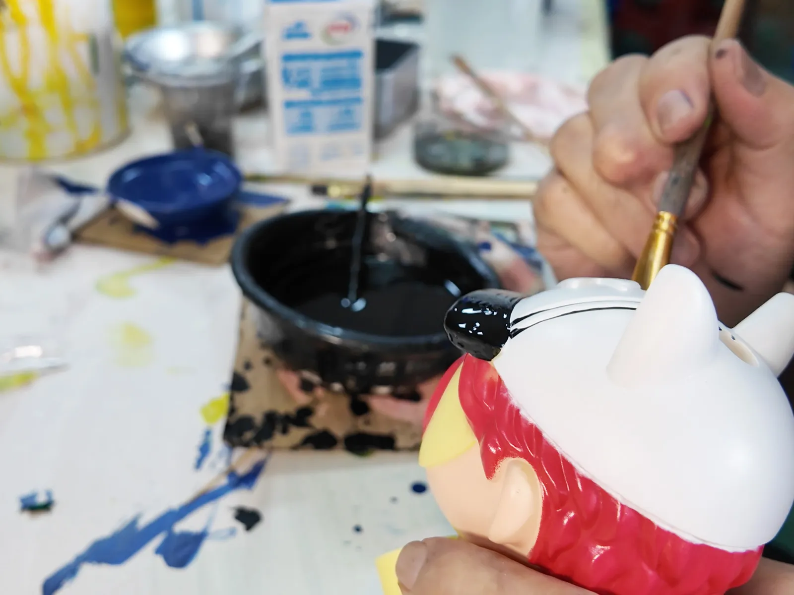 Draw lines with a paintbrush for fine detailing on toy figures